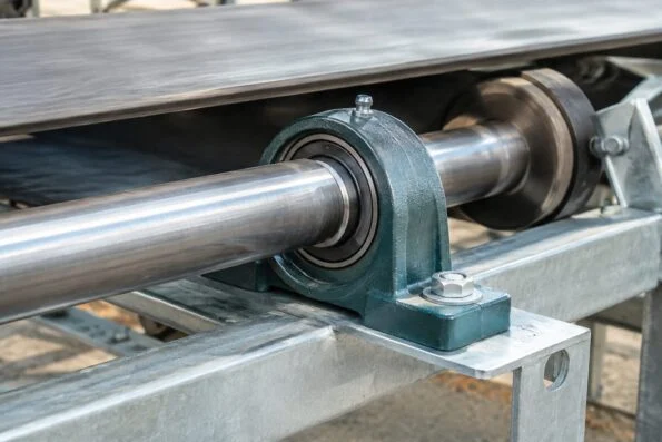 Pillow block bearing unit bolted to a conveyor frame with the shaft running through